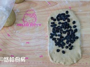 醒发后的面团压扁，上下擀开、翻面、再擀开，底边压薄，铺一层浸泡后的黑加仑，黑加仑用厨房纸蘸干水分再用。