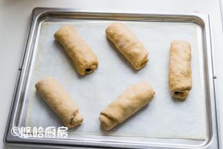 面团自上而下卷起卷紧，收口捏紧后摆放在烤盘上。烤盘放入烤箱中（不插电），下面放一碗热水进行二次发酵。