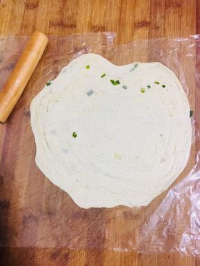 取出松弛好的面团放在保鲜袋上或者油纸上，擀成薄片。