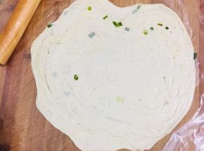 取出松弛好的面团放在保鲜袋上或者油纸上，擀成薄片。