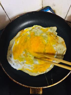 打入一颗鸡蛋，用筷子划散小火慢煎。
