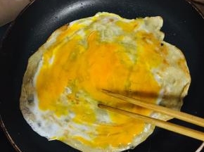 打入一颗鸡蛋，用筷子划散小火慢煎。