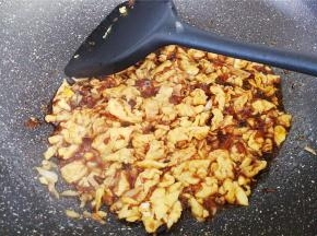 这时拿一个碗，放入1勺生抽，半勺老抽，2清水混合均匀倒入锅中鸡蛋里翻炒收汁。