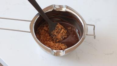 13.	纯可可脂巧克力币隔热水融化（水温不要超过50℃）后加入巧克力脆片拌匀。稍微放一会降温