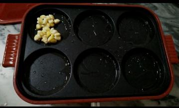 
4.六圆盘抹上油，油热后，倒入拌好的玉米，摊平。
