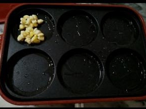 
4.六圆盘抹上油，油热后，倒入拌好的玉米，摊平。
