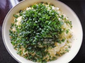 等待片刻后白菜出水，攥掉多余的水分，把小葱切细圈倒入白菜盆中混合。