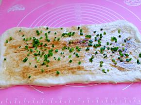 再撒上五香粉，再次用刷子刷至均匀，最后撒上葱花，从一端由里向外卷成一个大卷。