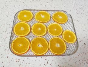 甜橙表皮用盐搓洗干净，切成薄片，摆在烤网上。