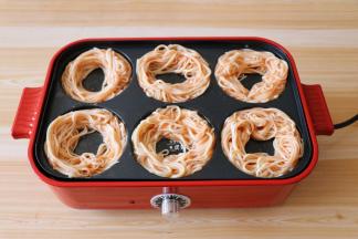 将拌好的面条一一放入圆盘里，围成中空的圆形；