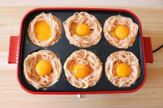 在面条圈中间放入蛋黄，盖上盖子继续煎5-8分钟即可关火，再刷适量牛排调味酱，撒上葱花就可以享用啦；