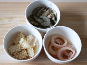明虾剪掉虾枪、挑出虾线和头部的内脏，跟鱿鱼花、鱿鱼圈一起清洗干净后加入适量生抽、料酒、盐腌制20分钟左右；