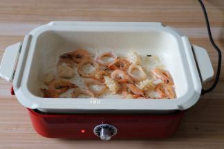 将虾、鱿鱼圈、鱿鱼花倒入锅内煸炒至变色；