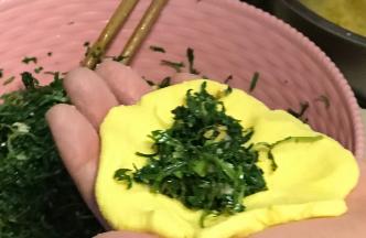 取一份玉米面团用手按扁，加入适量馅料。