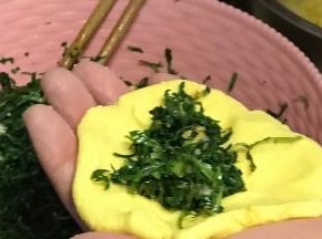 取一份玉米面团用手按扁，加入适量馅料。