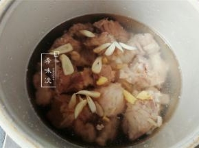 备一个高压锅，把沥干的排骨倒入，再放入切好的姜蒜和料酒，黑米醋。