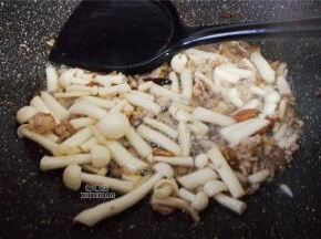 再接着放入洗净的白玉菇翻炒，倒入料酒继续翻炒下。