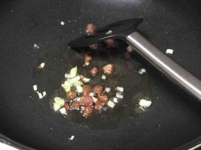 待腊肠粒出油后加入葱花翻炒。