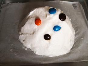 5.	烤盘中间铺上一张干净的油纸，用刮刀将蛋白糊弄到烤盘上，形成一个高高的小山状，再撒上几颗巧克力豆，
