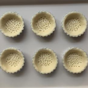 将面皮放入挞模具中，在底部用小叉子扎一些小孔，防止烘烤的时候挞皮膨胀。