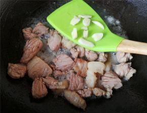 接着把切好的肉块放入煸炒会，炒制变色，把切片的蒜瓣放入继续翻炒出香味。