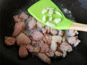 接着把切好的肉块放入煸炒会，炒制变色，把切片的蒜瓣放入继续翻炒出香味。