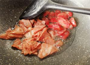 热锅倒入少量食用油，把切好的腊肠和培根下锅翻炒，煸出油脂。