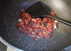 把小腊肠也斜刀切断，热锅倒油，把蒜瓣切片爆香，倒入腊肠段翻炒。