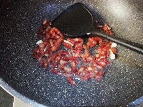 把小腊肠也斜刀切断，热锅倒油，把蒜瓣切片爆香，倒入腊肠段翻炒。