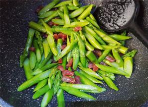 炒制片刻腊肠熟了，把沥干的芦笋倒入锅中跟食材一起翻炒。