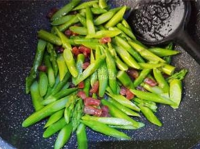 炒制片刻腊肠熟了，把沥干的芦笋倒入锅中跟食材一起翻炒。