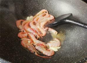 热锅倒入适量的油，把蒜瓣切片放入爆香，鲜虾洗净用牙签剔掉虾线，倒入锅中翻炒。
