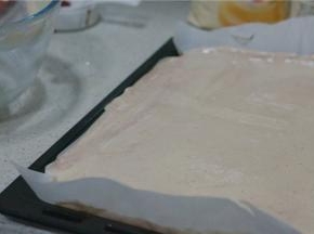 烤盘里铺上一纸烘焙纸，将拌好的面糊倒在里面，刮至平整。入烤箱180度烤制12分钟。