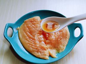 将两片鸡胸肉放入盘中，加入料酒。