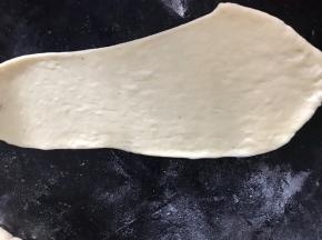 把醒发好的面团，用擀面杖擀成牛舌状的饼