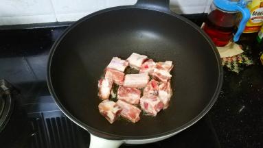 锅裏热油，放入排骨煎至金黄