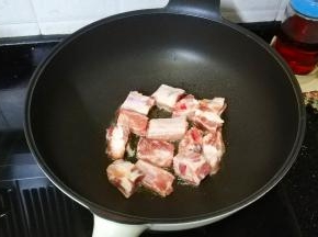 锅裏热油，放入排骨煎至金黄
