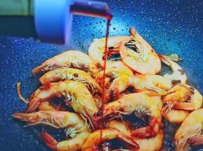 虾变红色后加入生抽与料酒，加少许糖调味，快速大火翻炒到虾肉全熟。