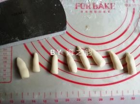 把32克的小面团搓成细长条，切成8份，并搓成一头尖的“蘑菇柄”