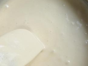 往刮刀上转圈快速倒入黄油与牛奶混合物!翻拌均匀!