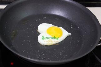 蛋黄外表凝固之后，把心形煎蛋模具往上提，鸡蛋立刻锅底，接着脱离开煎蛋模具，