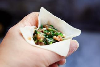 用手的虎口将云吞皮聚拢住馅料。