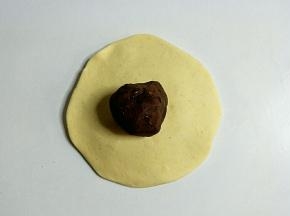 把面团擀成中间厚周边薄的薄饼，包入豆沙馅