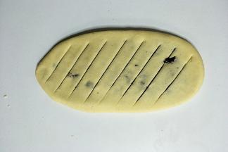 把面团擀成牛舌状，均匀斜划几刀，如图