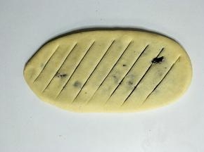 把面团擀成牛舌状，均匀斜划几刀，如图