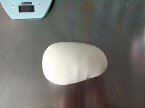 揉成光滑的面团后取出再手揉辅助排气，最后揉成超级无敌光滑的面团