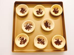 将蛋挞皮摆上烤盘，在中间撒上适量巧克力豆豆