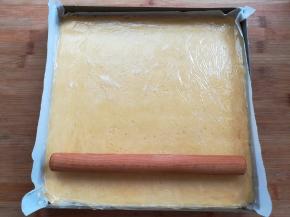 金盘里垫一张油纸，放入面团用擀面杖擀平