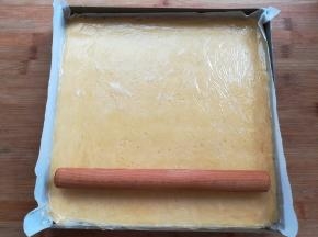 金盘里垫一张油纸，放入面团用擀面杖擀平