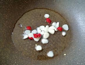 炒锅内倒适量的食用油烧热，下入蒜片和干红辣椒炒香。